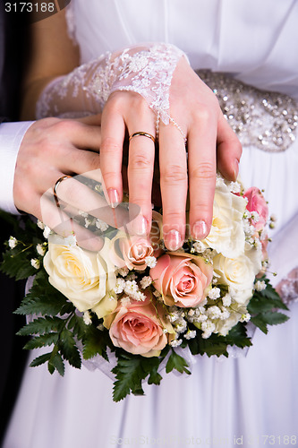 Image of Hands of the newlyweds with wedding bouquet