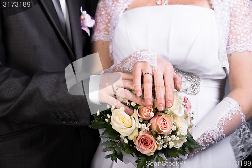 Image of Hands of the newlyweds with wedding bouquet