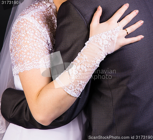 Image of bride hand on the back of the groom. Gentle loving hug