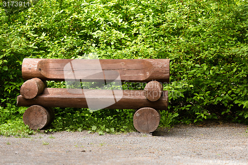 Image of wooden bench in the park on a background of vegetation