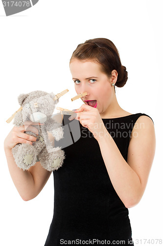 Image of attractive smiling brunette holding teddy bear grimacing with pe
