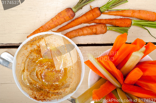 Image of fresh hummus dip with raw carrot and celery 