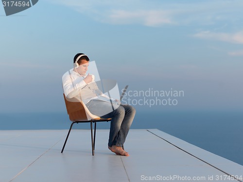 Image of relaxed young man at home on balcony