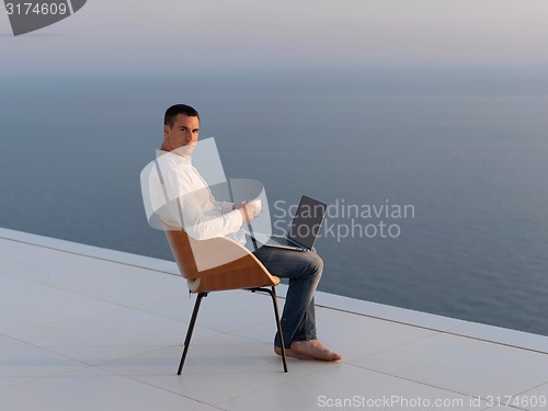 Image of relaxed young man at home on balcony