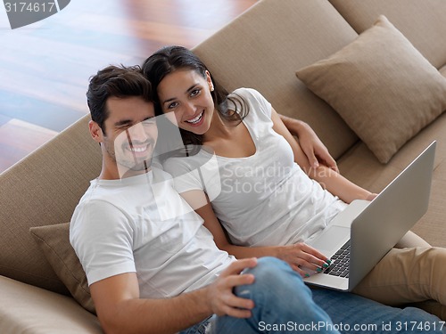 Image of relaxed young couple working on laptop computer at home