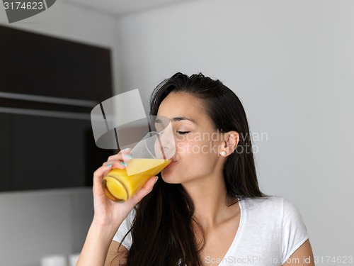 Image of woman drinking juice in her kitchen