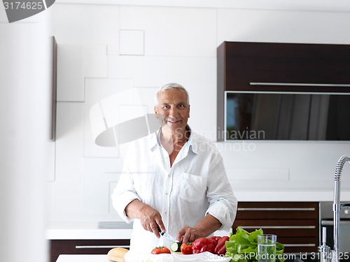 Image of man cooking at home preparing salad in kitchen