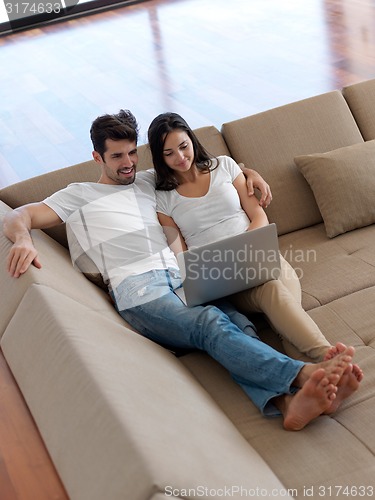 Image of relaxed young couple working on laptop computer at home