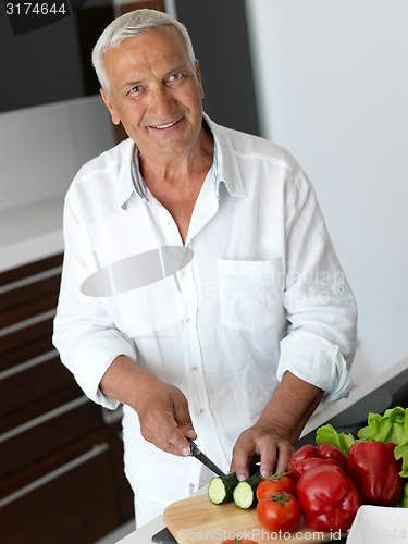 Image of man cooking at home preparing salad in kitchen