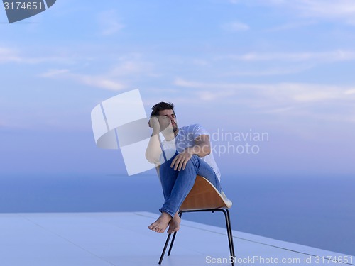 Image of relaxed young man at home on balcony