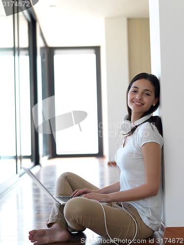 Image of relaxed young woman at home working on laptop computer