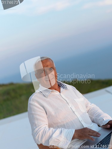 Image of relaxed senior man on balcony