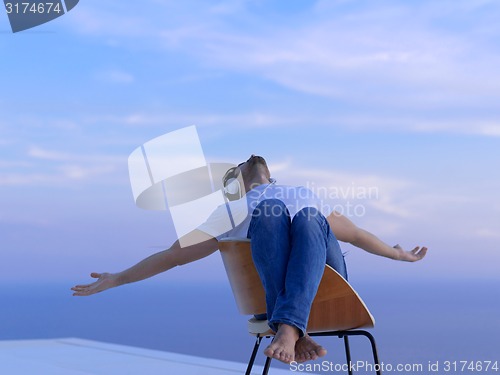 Image of relaxed young man at home on balcony