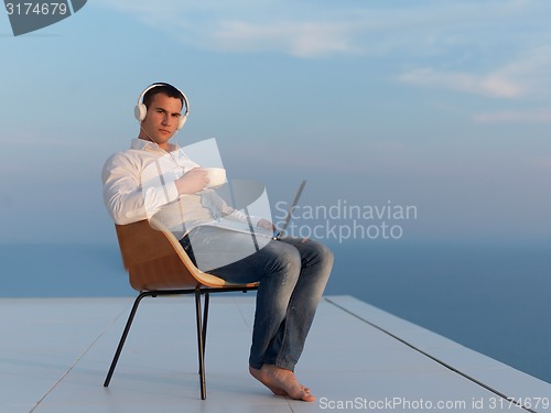 Image of relaxed young man at home on balcony