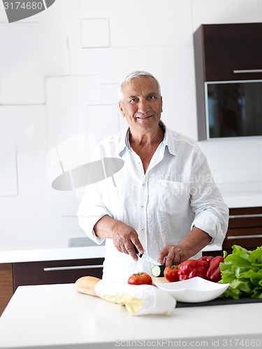 Image of man cooking at home preparing salad in kitchen