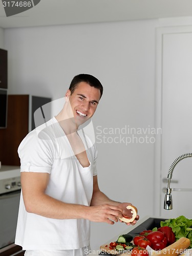 Image of man cooking at home preparing salad in kitchen