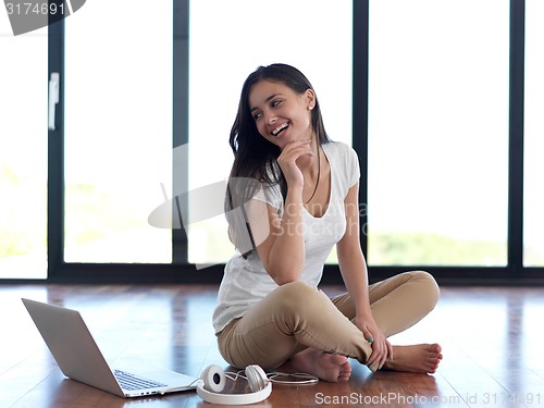 Image of relaxed young woman at home working on laptop computer