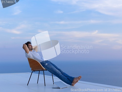 Image of relaxed young man at home on balcony