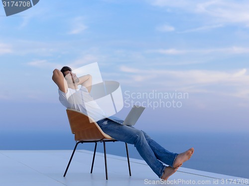 Image of relaxed young man at home on balcony