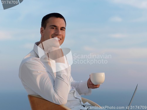 Image of relaxed young man at home on balcony