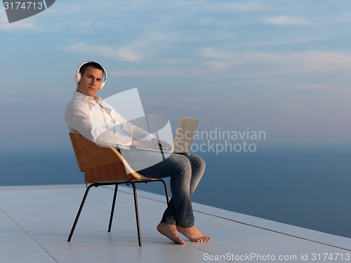 Image of relaxed young man at home on balcony