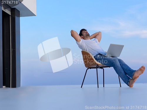 Image of relaxed young man at home on balcony