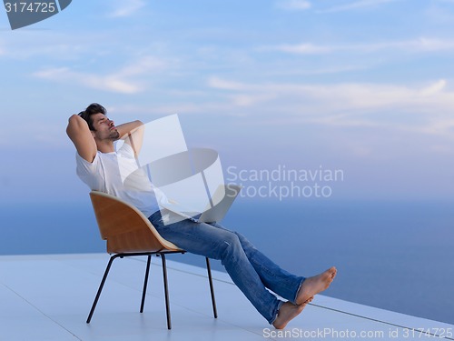 Image of relaxed young man at home on balcony
