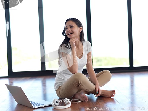 Image of relaxed young woman at home working on laptop computer