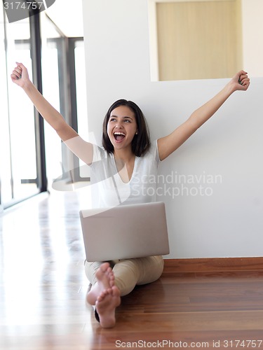 Image of relaxed young woman at home working on laptop computer