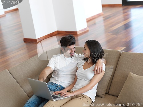 Image of relaxed young couple working on laptop computer at home