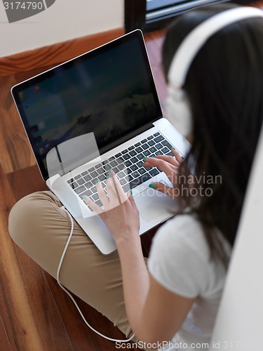 Image of relaxed young woman at home working on laptop computer