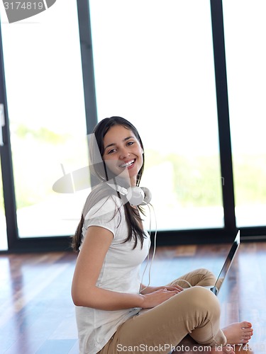 Image of relaxed young woman at home working on laptop computer