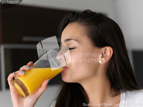 Image of woman drinking juice in her kitchen