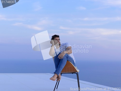 Image of relaxed young man at home on balcony