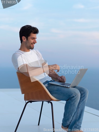 Image of relaxed young man at home on balcony