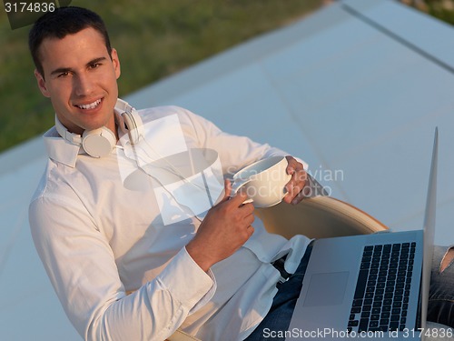 Image of relaxed young man at home on balcony