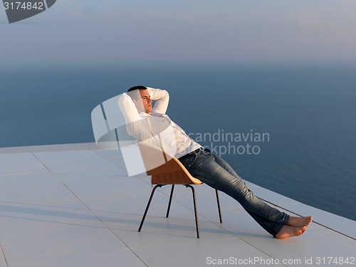 Image of relaxed young man at home on balcony