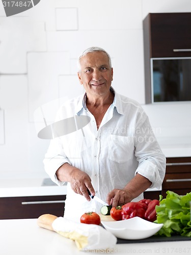 Image of man cooking at home preparing salad in kitchen