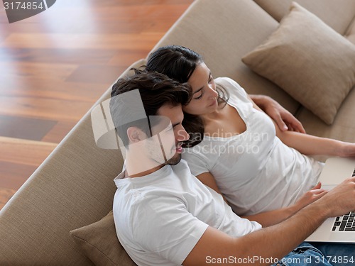 Image of relaxed young couple working on laptop computer at home