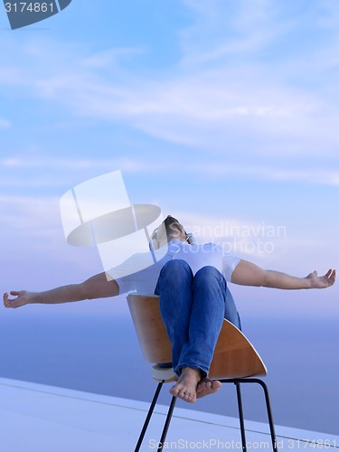Image of relaxed young man at home on balcony