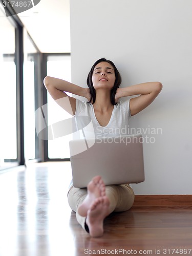 Image of relaxed young woman at home working on laptop computer