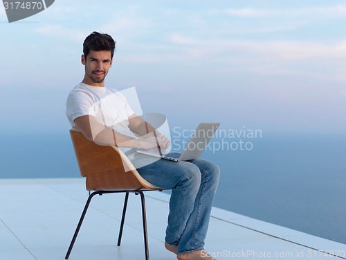 Image of relaxed young man at home on balcony