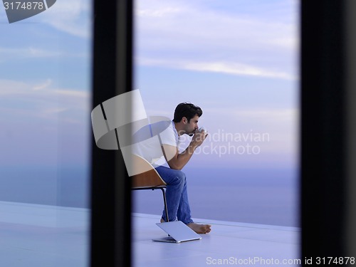 Image of relaxed young man at home on balcony