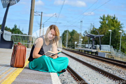 Image of Woman sitting on the station and reading