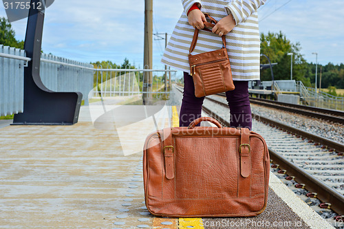 Image of Womans hands holding bag and suitcase at station