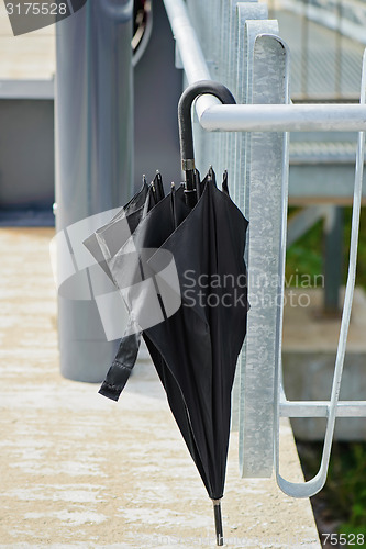 Image of Black umbrella hanging on the railing outside