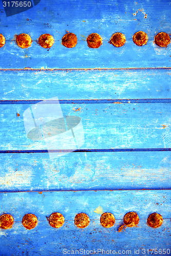 Image of dirty stripped paint in   blue wood door and rusty 