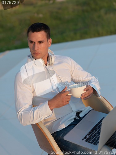 Image of relaxed young man at home on balcony