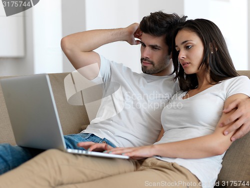 Image of relaxed young couple working on laptop computer at home