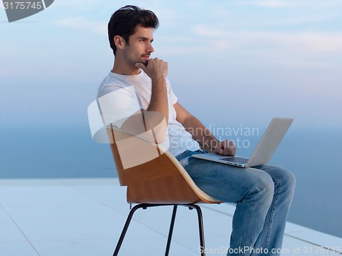 Image of relaxed young man at home on balcony